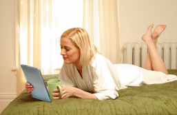 Foto: Leserin mit Tablet auf dem Bett liegend