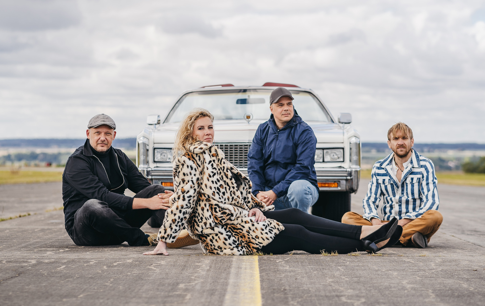 Foto: 4 Künstler sitzen vor einem Auto