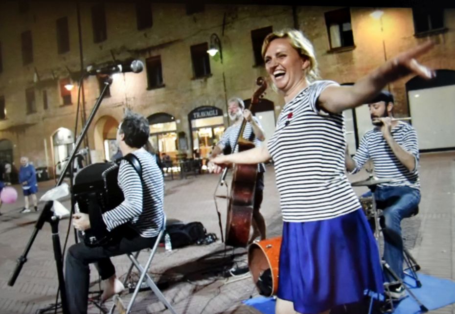 Eine frau und drei Männer stehen auf der Straße und machen Musik.