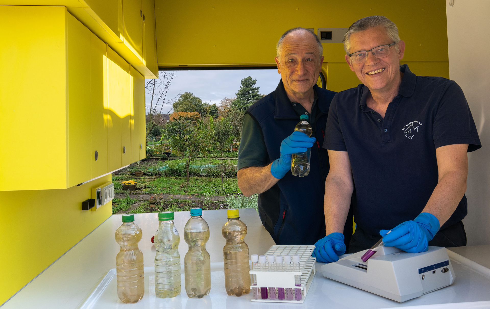 Foto: 2 Männer im gelben Mobil bei der Untersucheung von Wasserproben