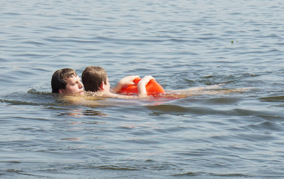 Foto: Rettungsschwimmer schwimmt im Wasser mit einem zu Rettenden im Arm