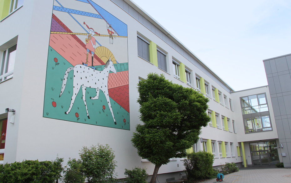 Foto: Schulhof und Schule mit Wandbild