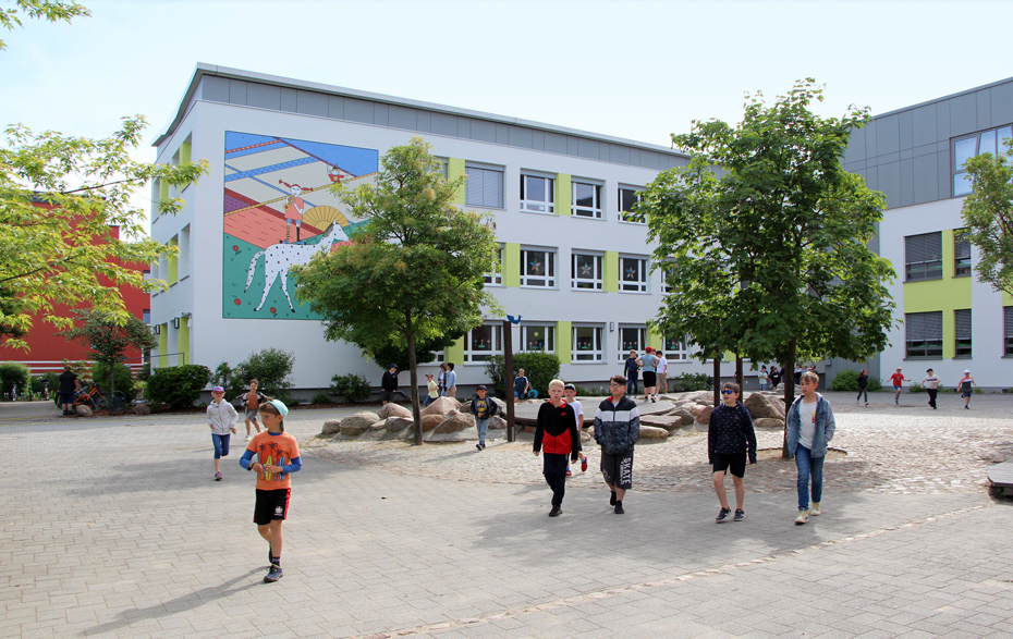Foto: Schulhof mit Schülern vor dem Schulgebäude