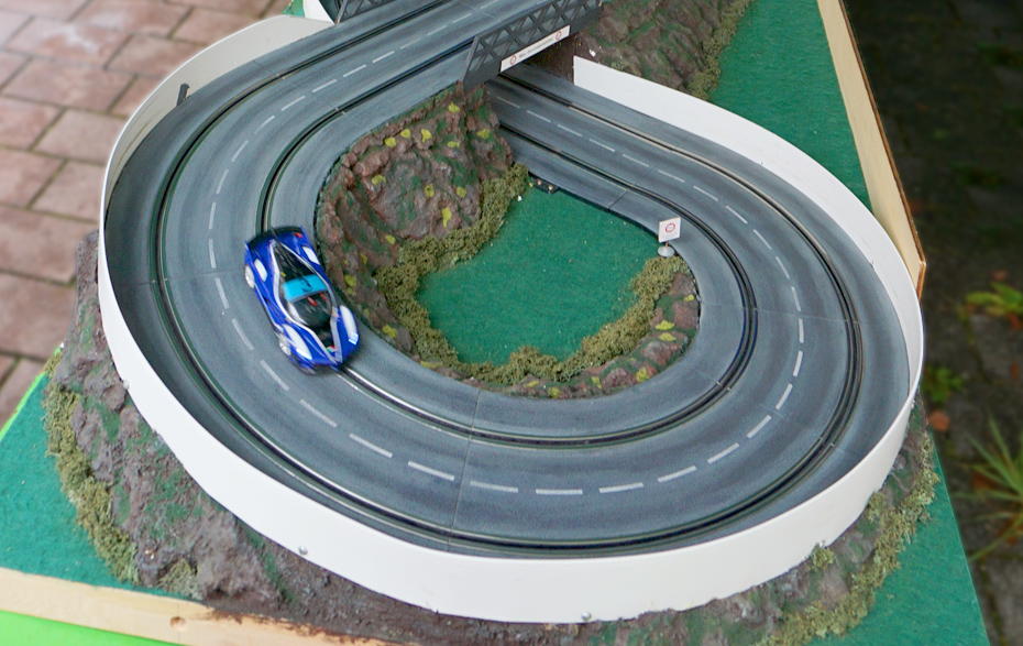 Foto: blaues Auto in der Spur einer Autorennbahn