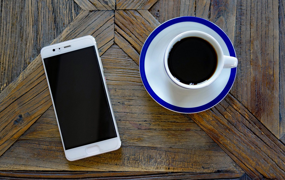 Foto: Handy und Kaffeetasse auf einem Holztisch