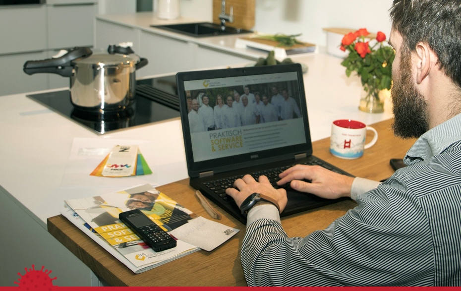 Foto: Mann mit Laptop neben der Küche mit Topf auf dem Herd