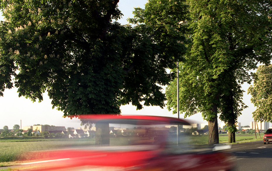 Foto: Rotes Auto fährt rasant vorbei.
