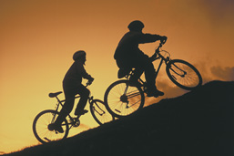 Foto: zwei Radfahrer berganfahrend im Gegenlicht