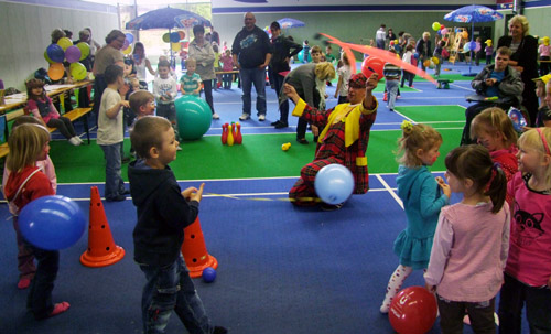 Foto: Ein Clown unterhält mit Bändern, die um ihn herum spielenden Kleinkinder.