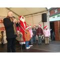 Foto: Herr Polzehl steht auf der Bühne und neben ihm der Weihnachtsmann und eine Kindergruppe.