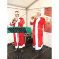 Foto: Zwei Musiker im Weihnachtsmannkostüm spielen Trompete.