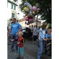 Foto: Mann verkauft Heliumluftballons, Leute stehen und erzählen.