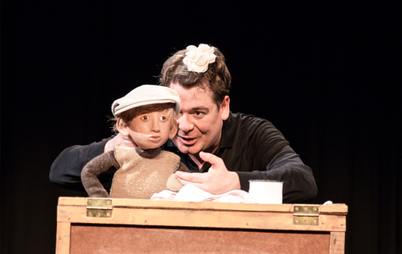 Foto: Schauspieler und Puppe hinter einer Kiste