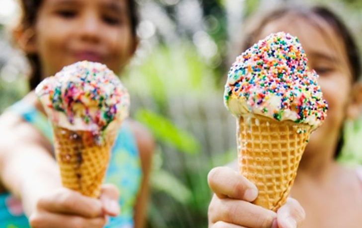 Foto: 2 Mädchen halten ihre Eiswaffeln mit Zuckerperlen vor sich ins Bild.