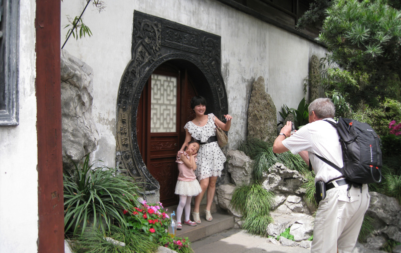 Foto: Mann fotografiert chinesische Mutter mit Kind vor einem Hauseingang