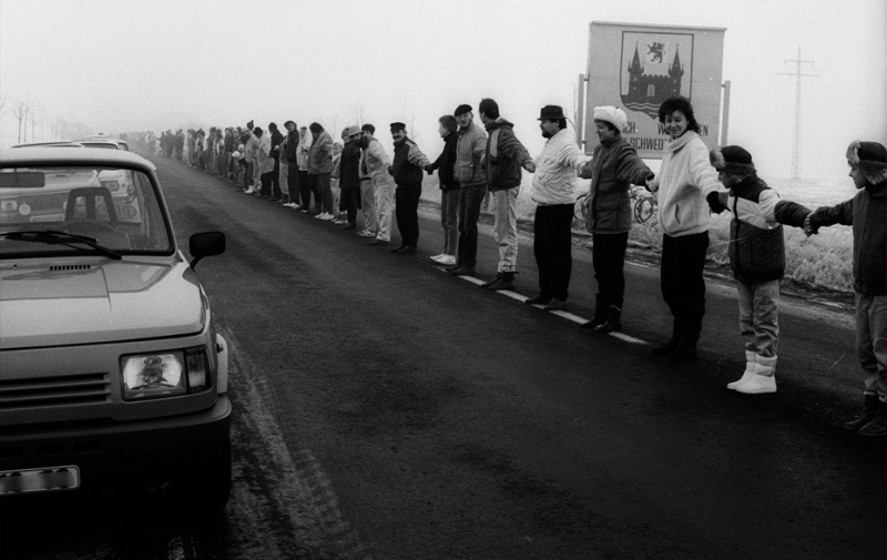 Schwarz-Weiß-Foto: Menschenkette an der Straße