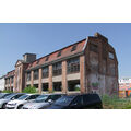 Foto: Schrägansicht des Gebäudes der ehemaligen Mineralwasserfabrik, davor parken Autos