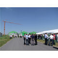 Foto: Blick zur Baustelle Biogasanlage mit Kran und einem Festzelt mit Gästen rechten rechten Bildbereich