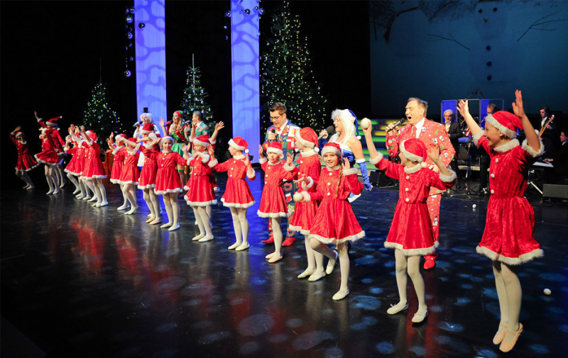 Foto: Kindertanzgruppe und Sänger in weihnachtlichen Kostümen